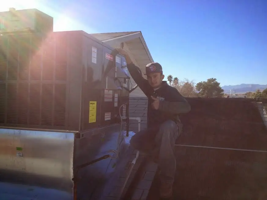 HVAC technician performing AC Tune-Up on a rooftop unit in New Castle